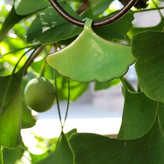 Ein elegantes Bijou neben einem inspirierenden Ginkgo-Blatt, das als Quelle der Inspiration für dieses wunderschöne Schmuckstück dient.